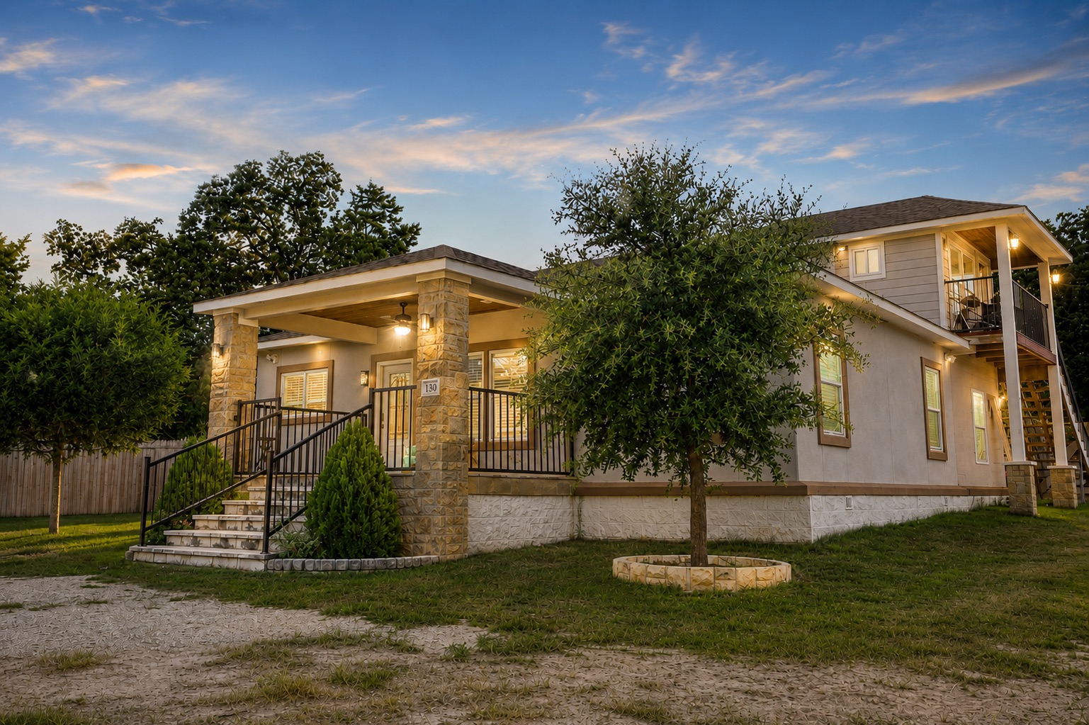 130 Los Arcos Road Elgin, TX 78621 - Photo 1 of 39 A welcoming front entrance with stone accents and a covered porch leads to this charming residence, framed by mature trees.