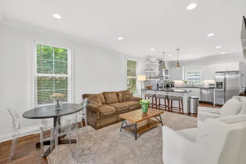 a living room kitchen with couches and kitchen view with wooden floor
