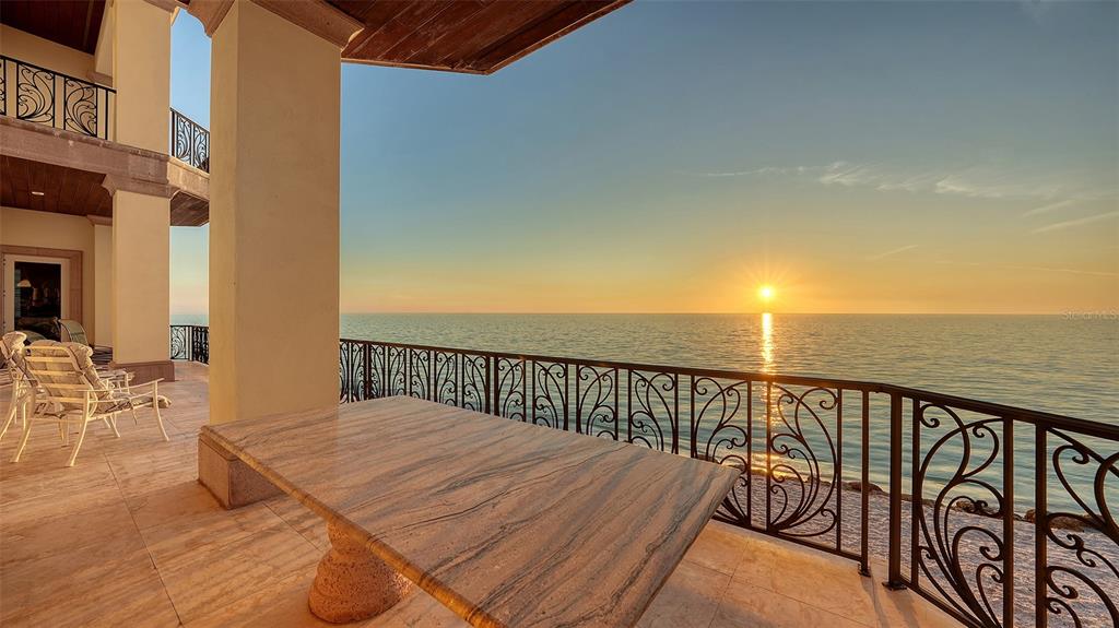 a balcony with wooden floor table and chairs
