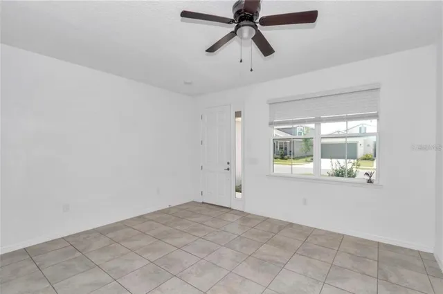 a view of empty room with window and ceiling fan