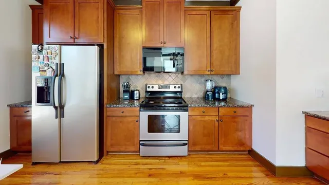 a kitchen with stainless steel appliances granite countertop a refrigerator a stove and a sink