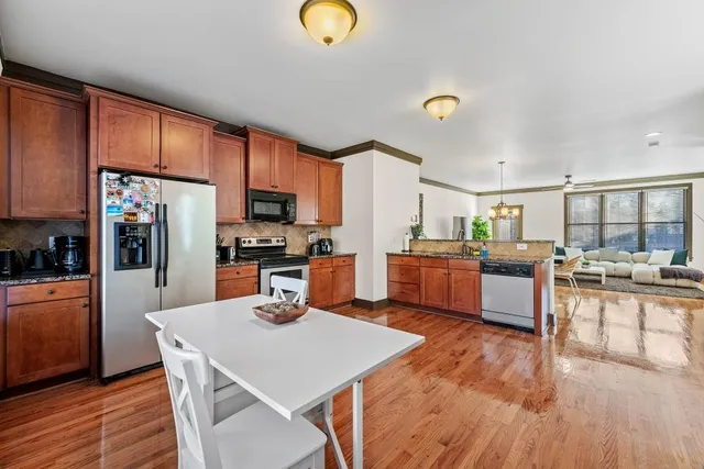 a kitchen with stainless steel appliances wooden floor dining table and chairs