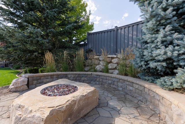 687 South 2080th Street East Springville, UT 84663 - Photo 105 of 149 Outdoor stone patio featuring a built-in fire pit with decorative stone, flagstone paving, a block retaining wall, and mature landscaping with a privacy fence