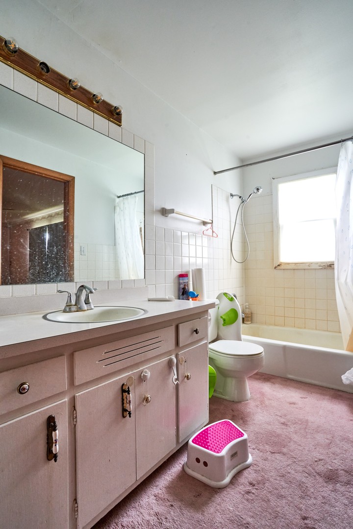 24W175 Hobson Road Naperville, IL 60540 - Photo 20 of 30 a bathroom with a sink a bathtub cabinets and a window