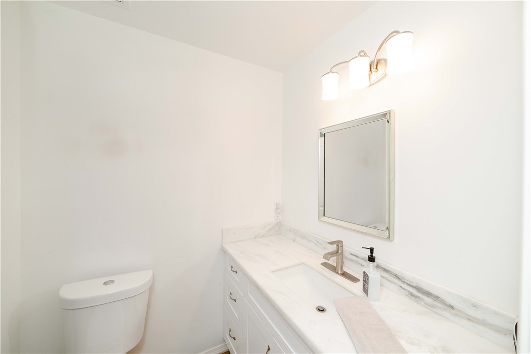 2948 Pinal Road Golden Valley, AZ 86413 - Photo 18 of 59 Bathroom featuring a white toilet, framed mirror, and a vanity with a white countertop, undermount sink, and brushed nickel faucet