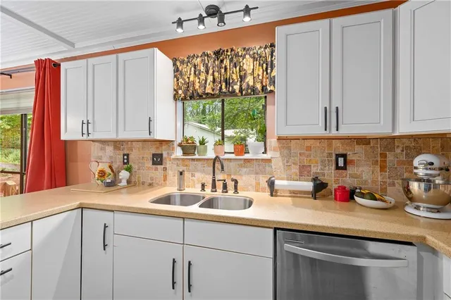 a kitchen with stainless steel appliances a sink a window and cabinets