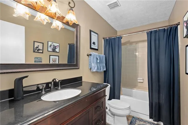 a bathroom with a granite countertop sink mirror vanity and toilet
