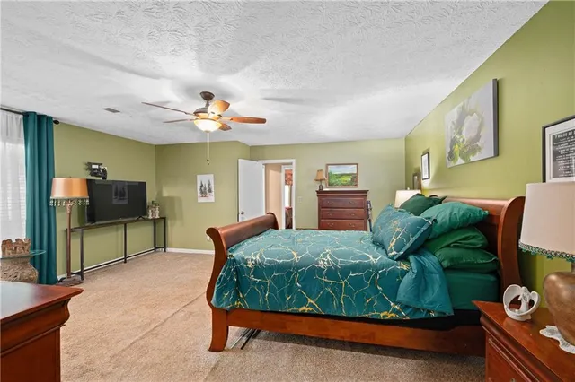 a bedroom with a bed and a flat tv screen on dresser