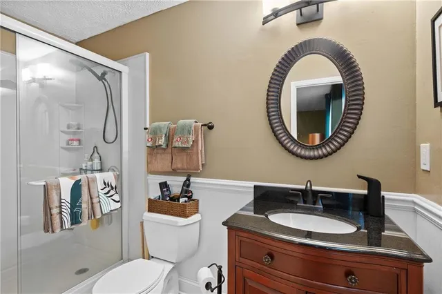 a bathroom with a granite countertop toilet a sink and a mirror
