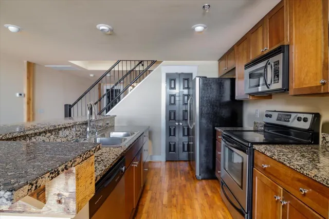 a kitchen with granite countertop a sink a counter top space stainless steel appliances and cabinets