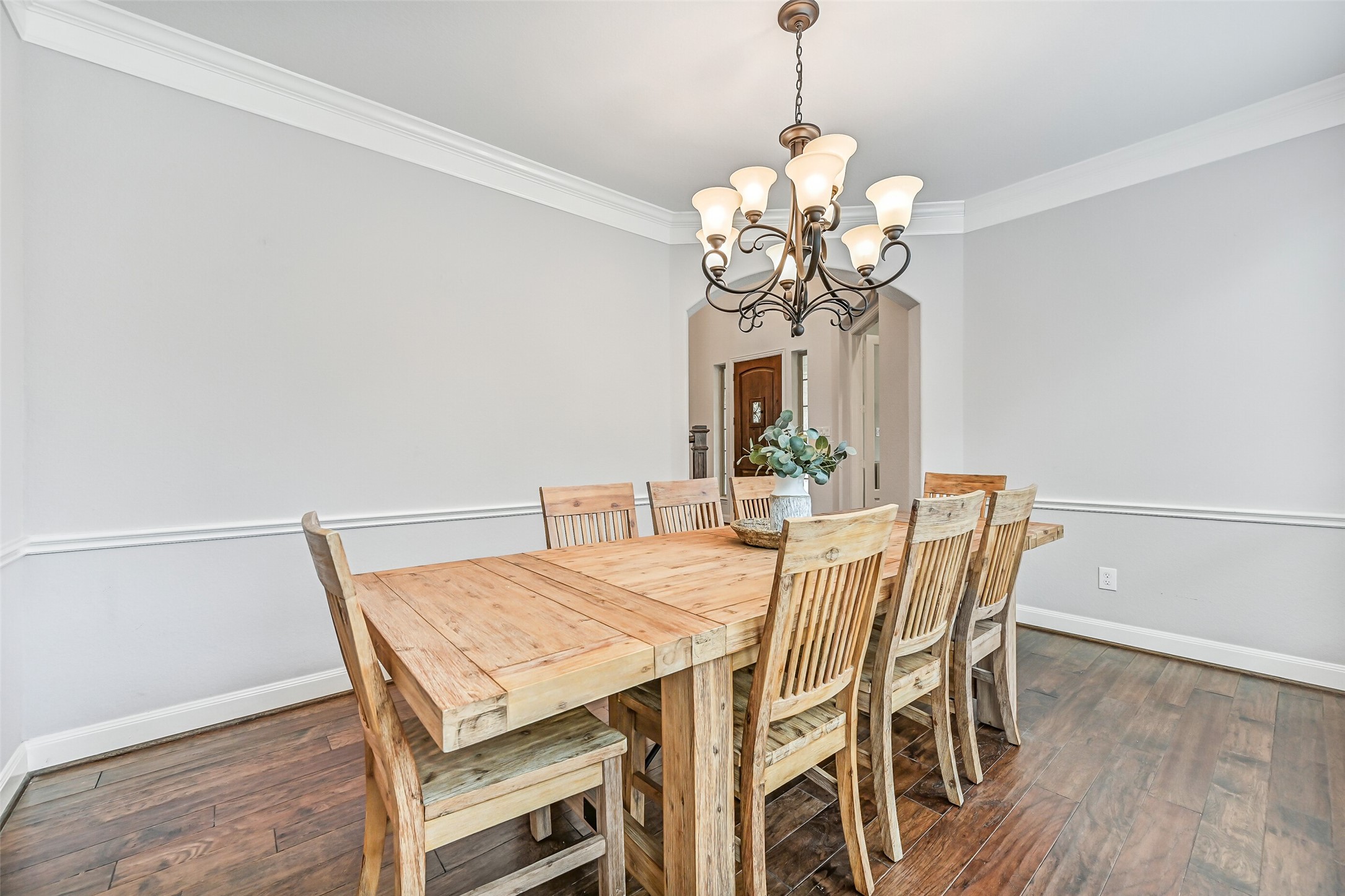 1008 Point Isabel Lane Friendswood, TX 77546 - Photo 10 of 50 Continue into a formal dining room with rich wood flooring, crown and chair rail molding, and a scrolled iron chandelier. The space offers generous room for a full dining set and sits conveniently between the foyer and kitchen for easy entertaining flow.