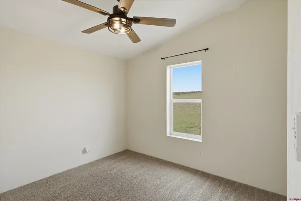an empty room with a window and a fan