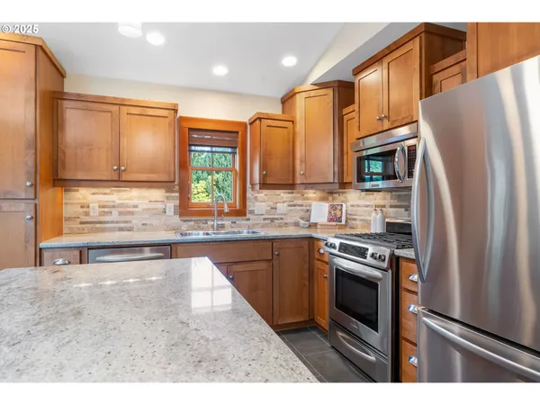 a kitchen with stainless steel appliances granite countertop a refrigerator a stove a sink and a microwave