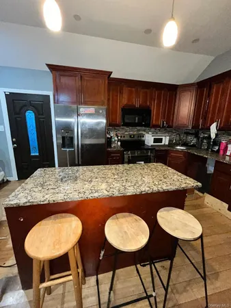 a kitchen with stainless steel appliances granite countertop a table chairs sink and refrigerator