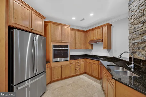 a kitchen with stainless steel appliances granite countertop a sink a stove and a refrigerator