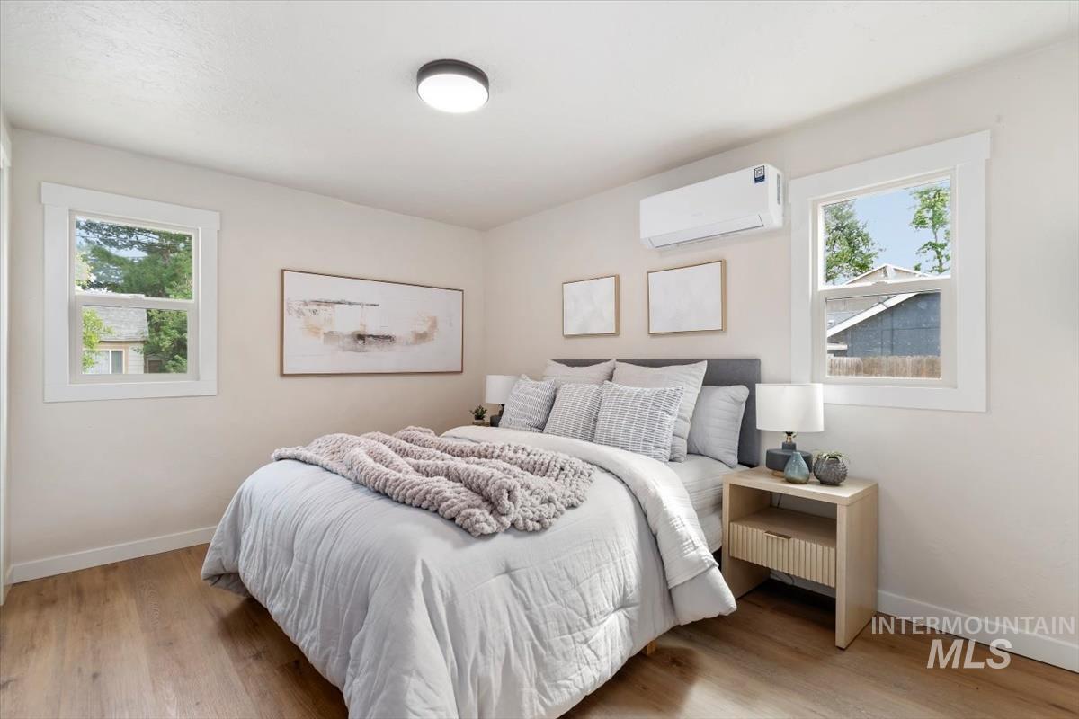 3005 West Hester Street Boise, ID 83702 - Photo 22 of 32 Bedroom featuring wood-finish flooring, two window openings with white trim, and a wall-mounted mini-split unit