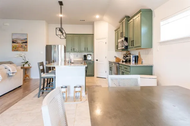 a kitchen with stainless steel appliances kitchen island granite countertop a sink a stove and a wooden floors