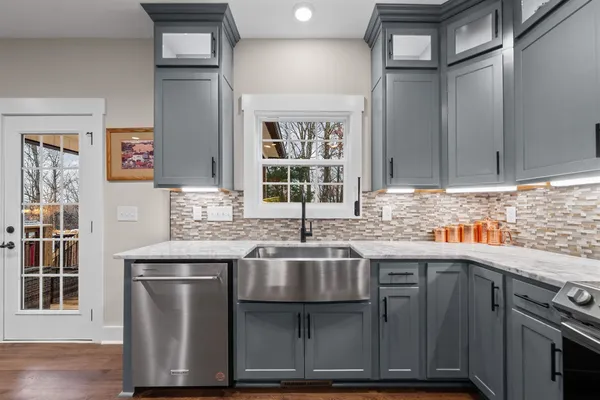 a kitchen with stainless steel appliances granite countertop a refrigerator a stove top oven a sink dishwasher a dining table and chairs with wooden floor
