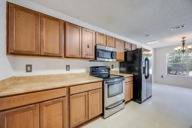 a kitchen with stainless steel appliances granite countertop a stove a sink dishwasher and a refrigerator with wooden cabinets