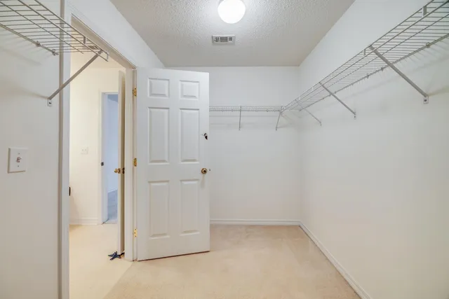 an empty room with chandelier fan and windows