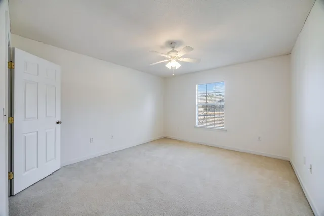 an empty room with closet and a ceiling fan