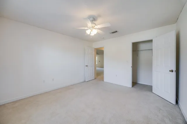 an empty room with a chandelier fan and windows