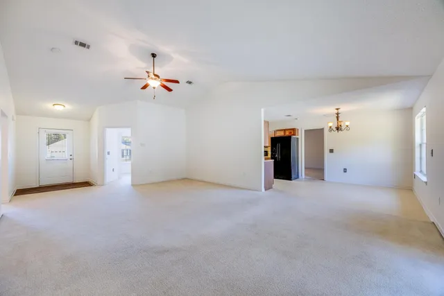 an empty room with an entryway and a chandelier fan
