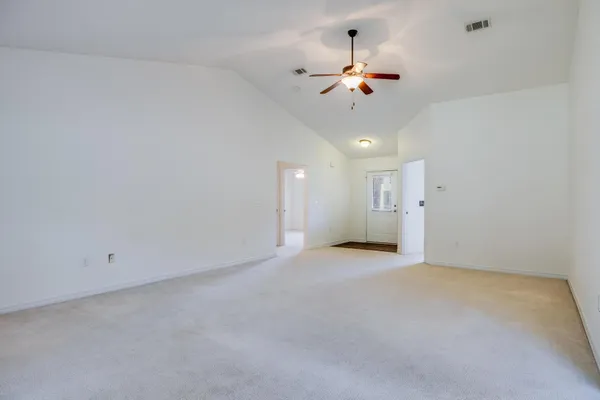 a view of an empty room with a chandelier fan