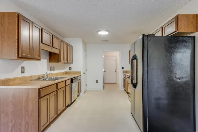 a kitchen with stainless steel appliances granite countertop a refrigerator a sink and a stove