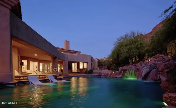 a view of pool with lawn chairs and plants
