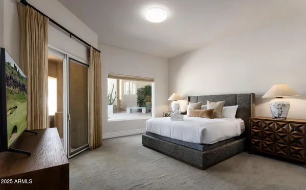 a bedroom with a bed and a flat tv screen on dresser