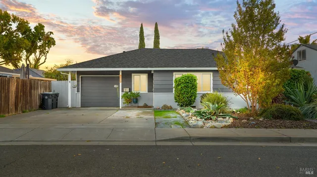 a front view of a house with a yard and potted plants