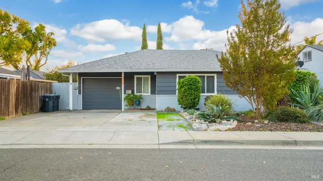 a front view of a house with a yard and potted plants