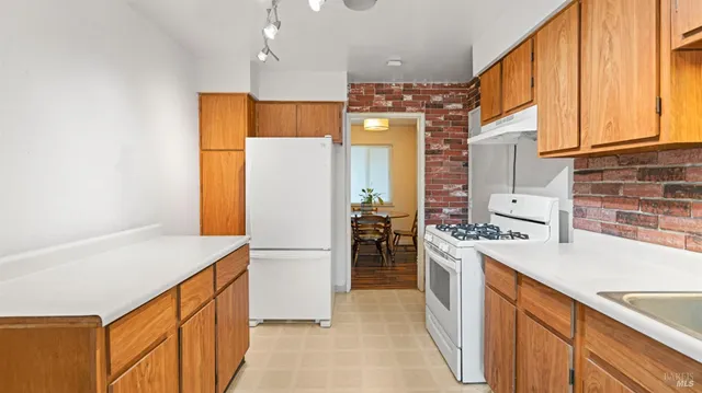a kitchen with a refrigerator a stove and a sink with wooden floor