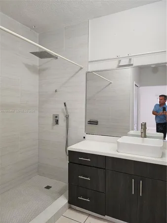 a bathroom with a shower sink vanity and mirror
