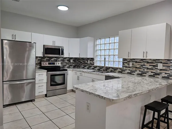 a kitchen with kitchen island granite countertop a stove sink and refrigerator