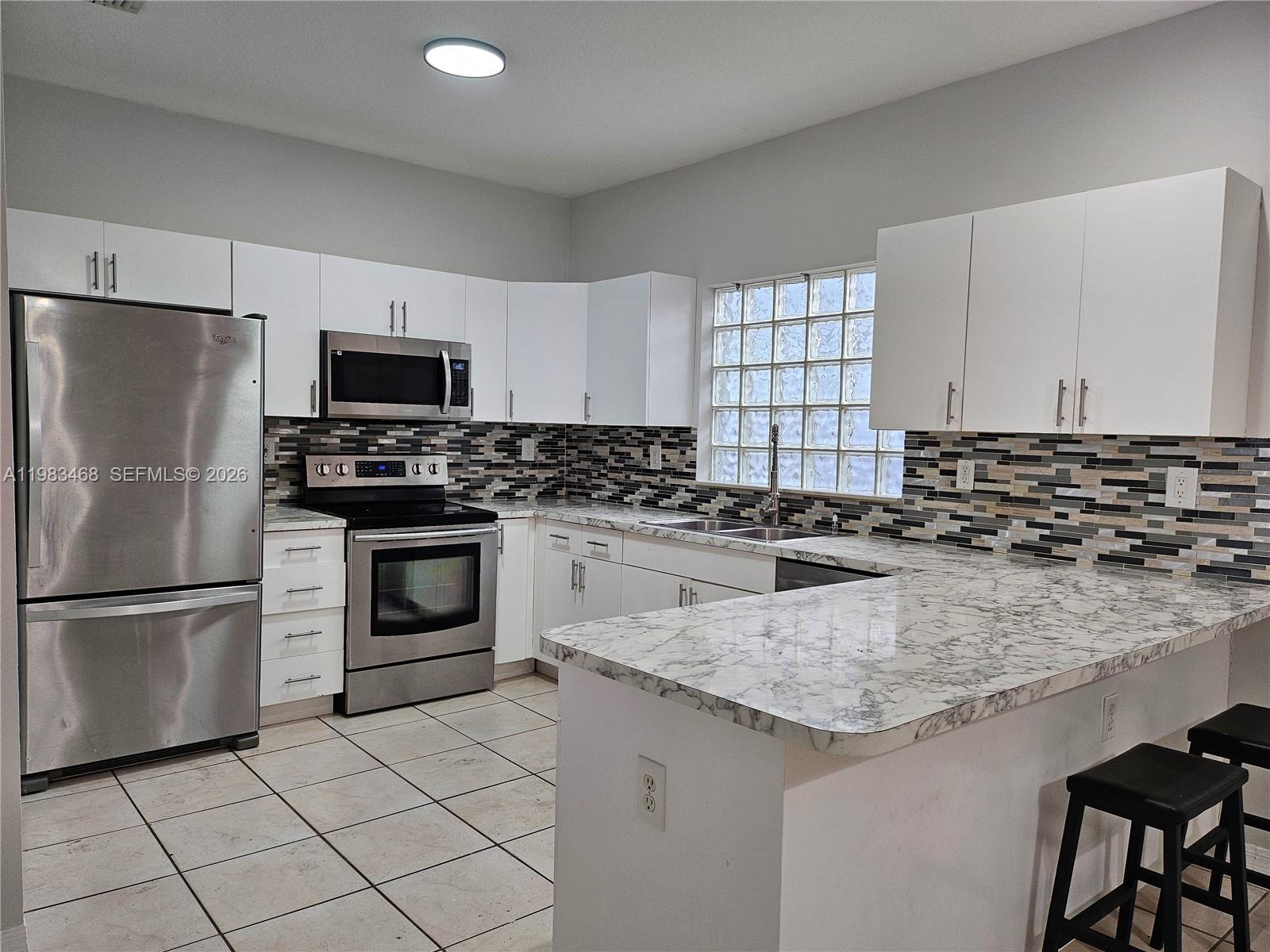 14924 Southwest 58th Street Miami, FL 33193 - Photo 17 of 17 a kitchen with kitchen island granite countertop a stove sink and refrigerator