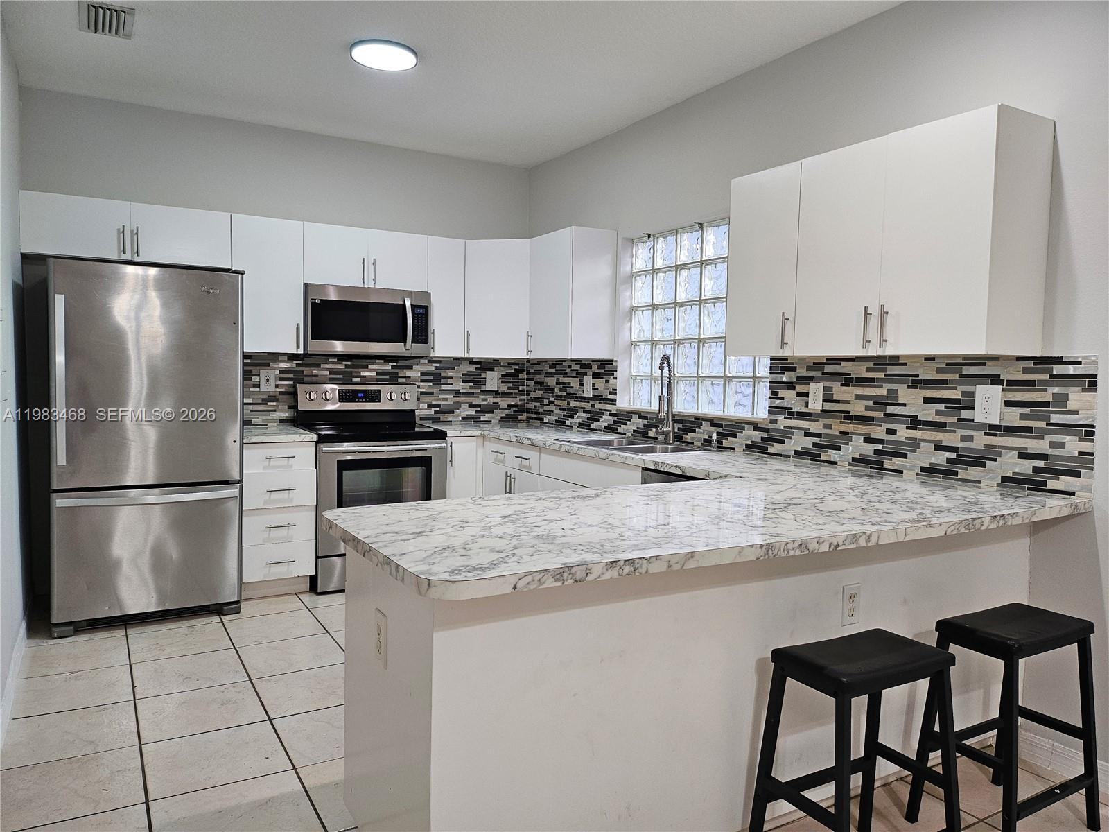 14924 Southwest 58th Street Miami, FL 33193 - Photo 6 of 17 a kitchen with stainless steel appliances granite countertop a stove a sink a microwave a refrigerator and white cabinets