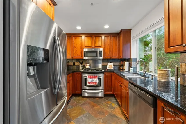 a kitchen with stainless steel appliances granite countertop a refrigerator a sink and a stove