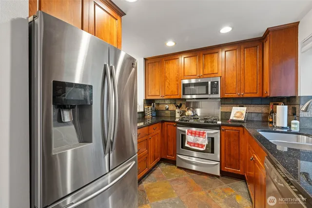 a kitchen with stainless steel appliances granite countertop a refrigerator and a stove top oven