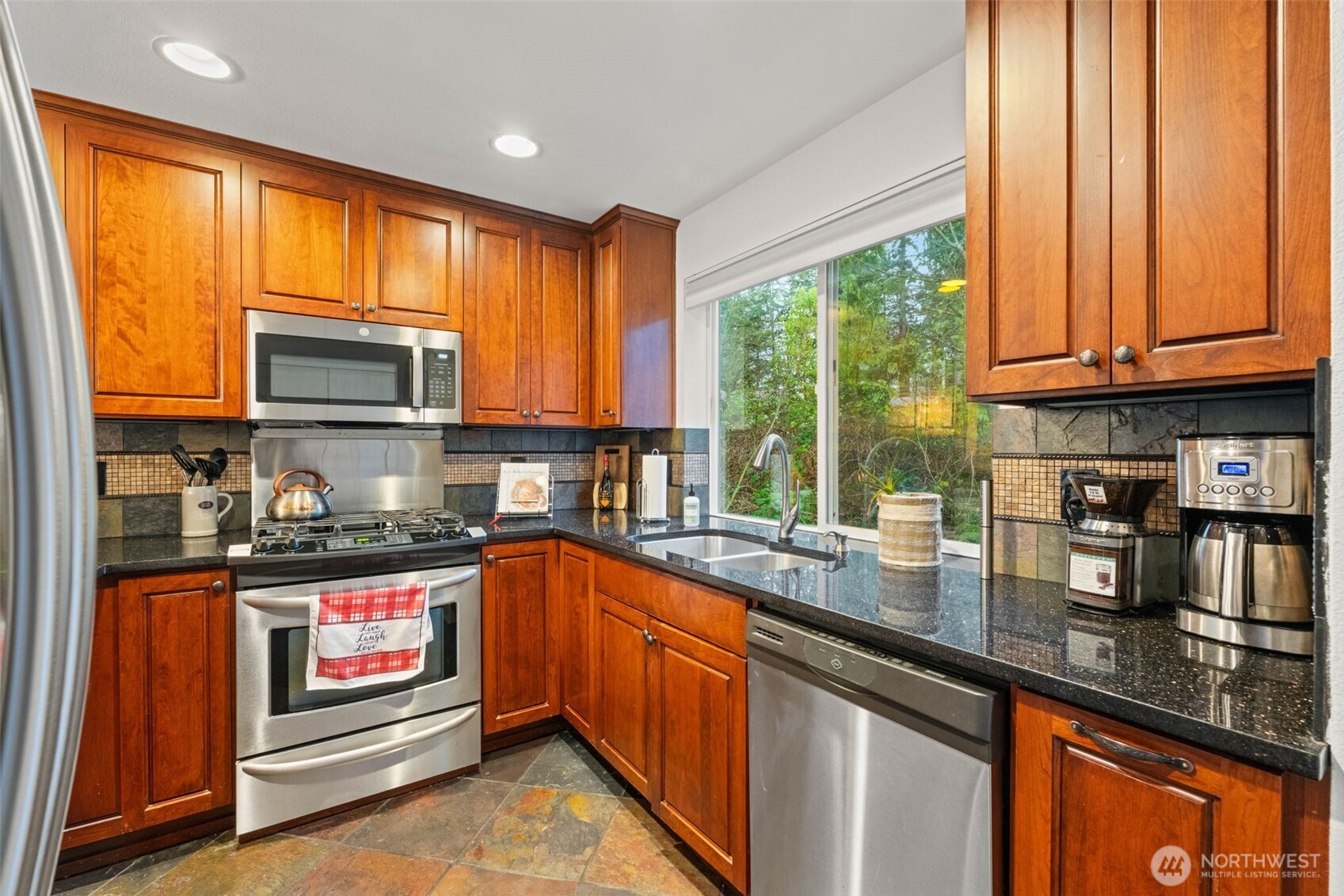 14714 53rd Avenue West, Unit 104 Edmonds, WA 98026 - Photo 10 of 35 a kitchen with stainless steel appliances granite countertop a stove a sink and a microwave