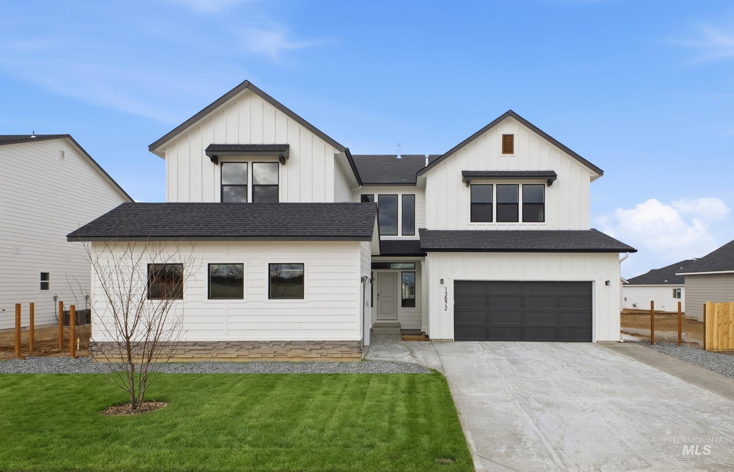 Modern farmhouse style home with a shingled roof, board and batten siding, an attached garage, and concrete driveway
