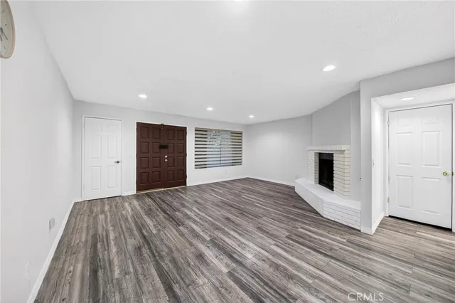 a view of empty room with wooden floor and fireplace