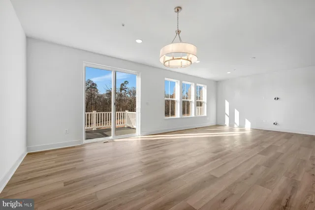 a view of an empty room with wooden floor and windows