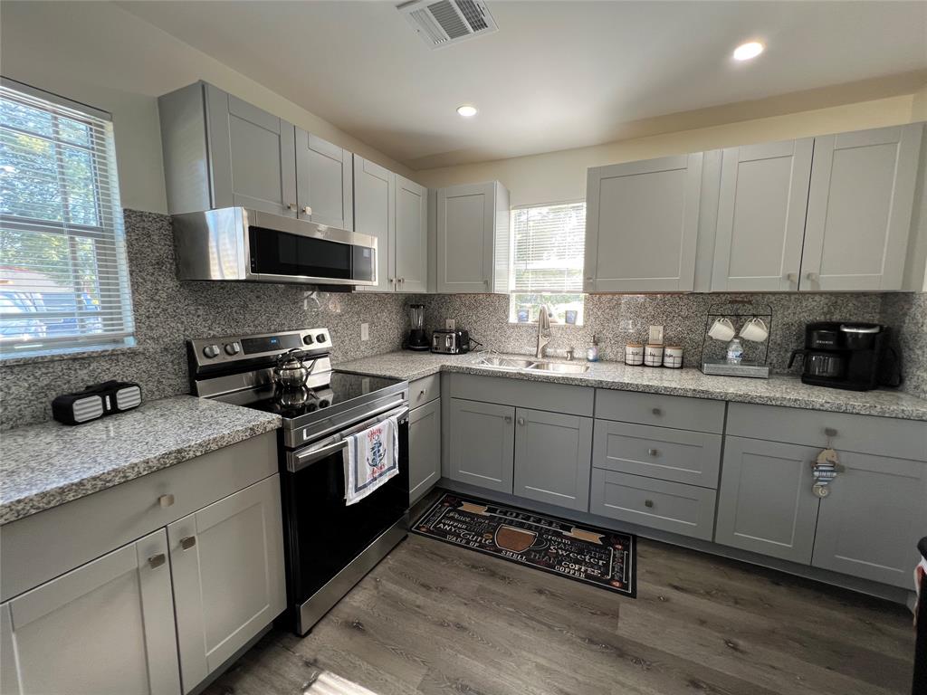 a kitchen with granite countertop white cabinets stainless steel appliances a sink and a window