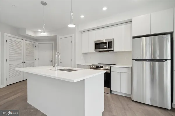a kitchen with stainless steel appliances granite countertop a refrigerator a sink dishwasher a stove with white countertops and wooden floor