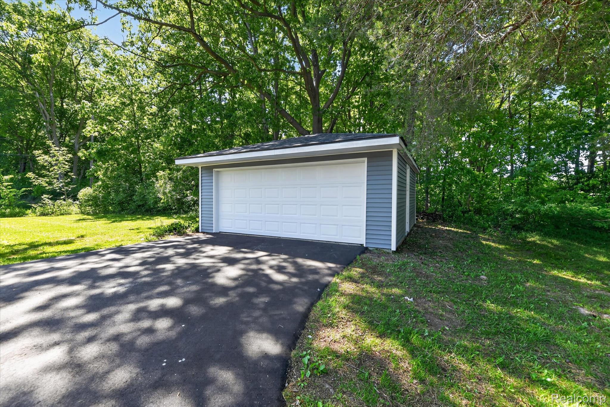2250 Montague Road Davison, MI 48423 - Photo 45 of 45 Detached garage featuring blue siding, white trim, a white panel garage door, dark shingle roofing, and an asphalt driveway