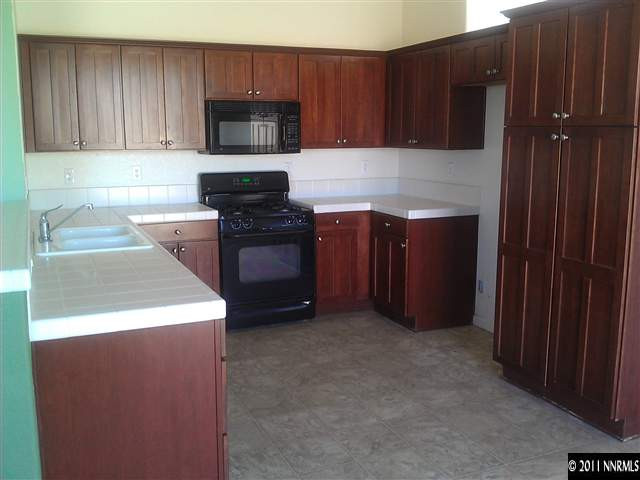 5040 Coggins Road Reno, NV 89506 - Photo 5 of 6 a kitchen with granite countertop wood cabinets and stainless steel appliances