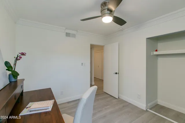 an empty room with wooden floor ceiling fan and window