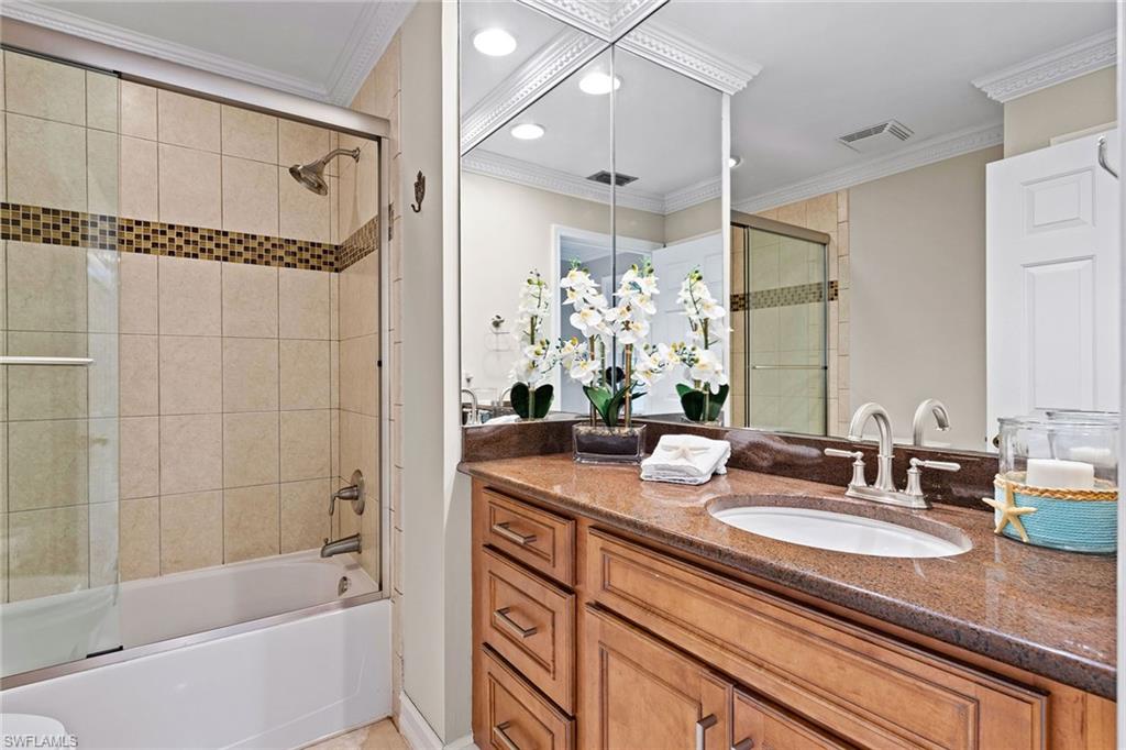 9101 Vanderbilt Drive, Unit 301 Naples, FL 34108 - Photo 16 of 28 a bathroom with a granite countertop sink a mirror a shower and a bathtub
